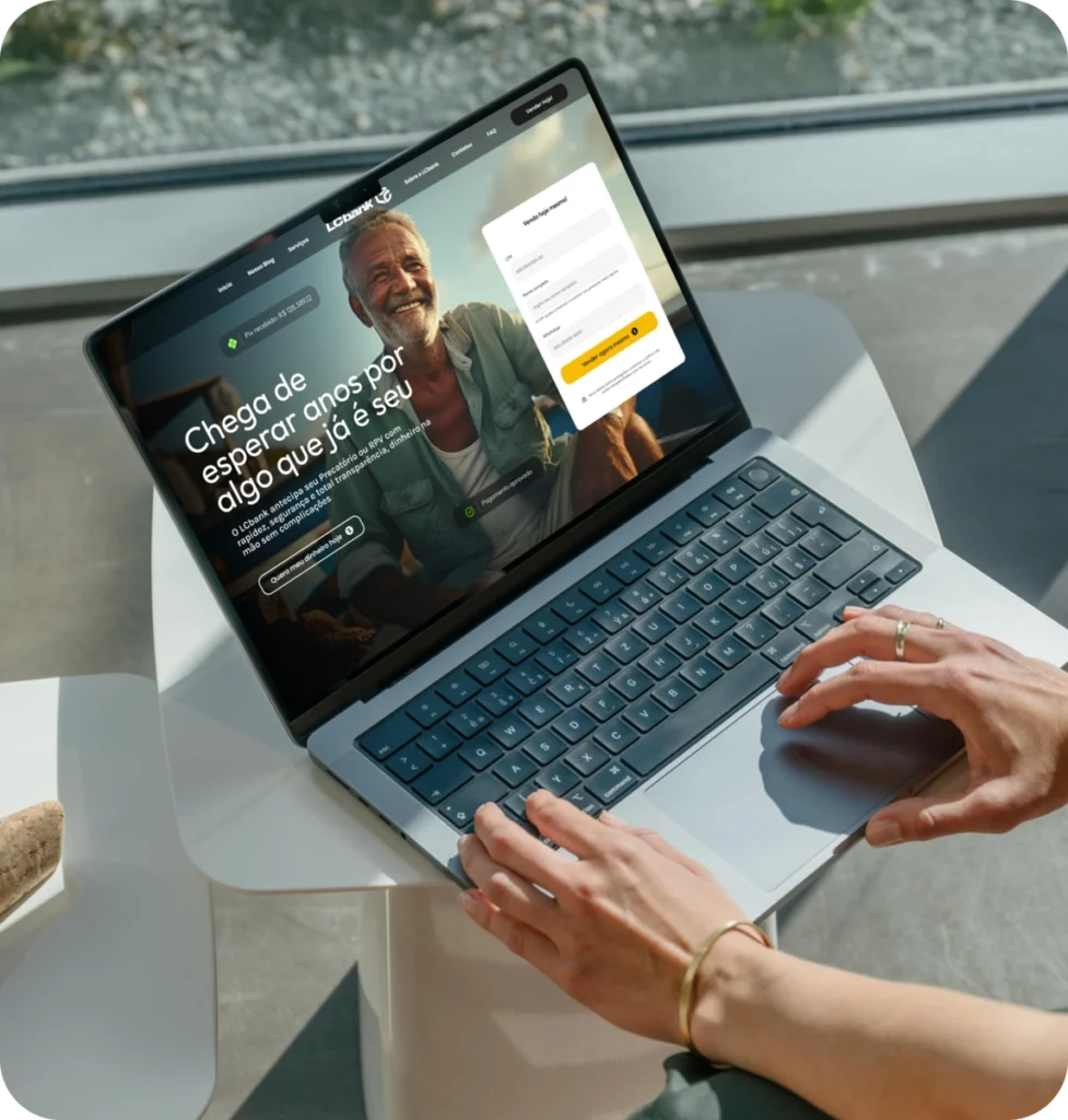 Laptop aberto exibindo o site do LCbank, com foco na página inicial.